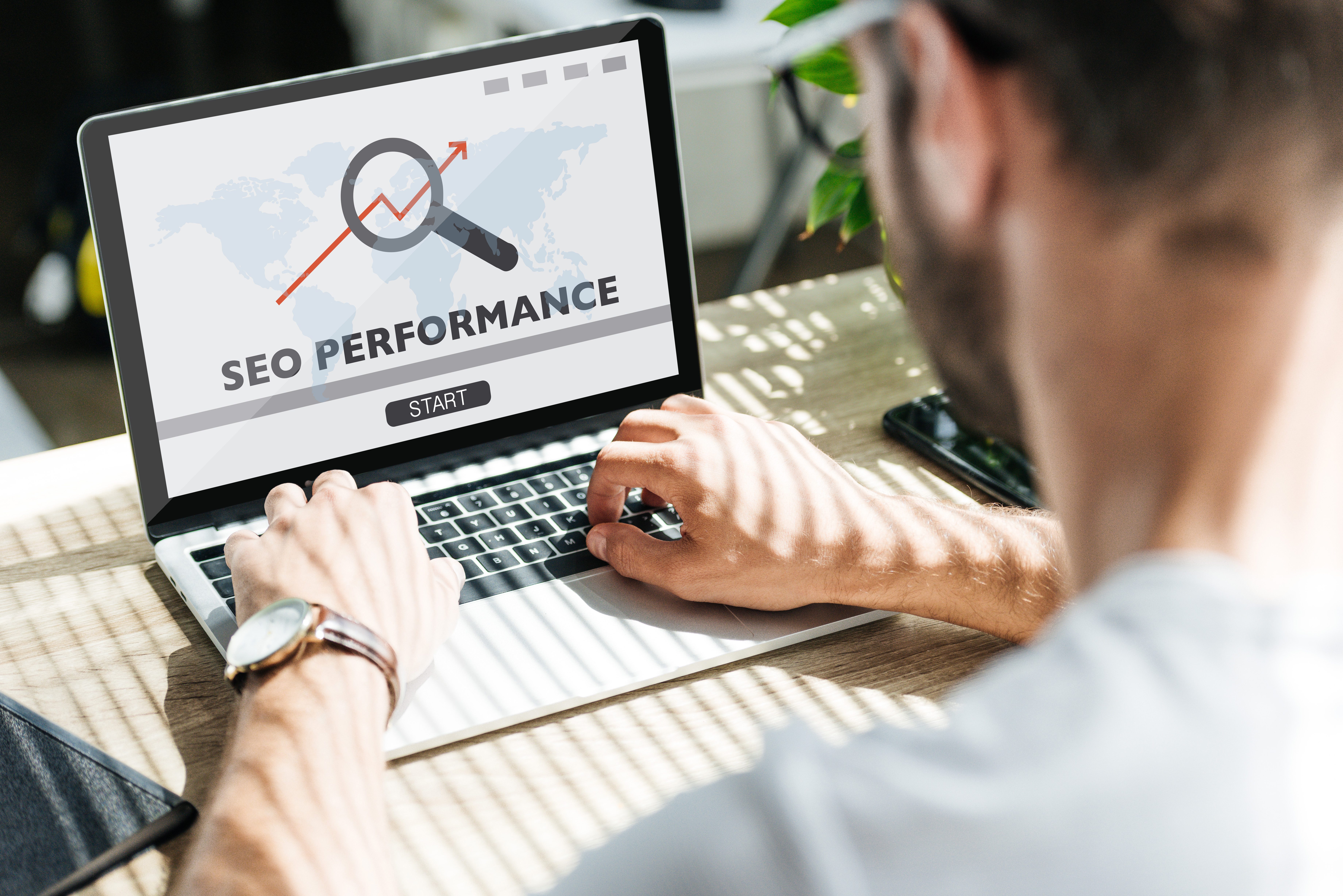 Man typing on a laptop showing an SEO performance page with magnifying glass and upward growth arrow