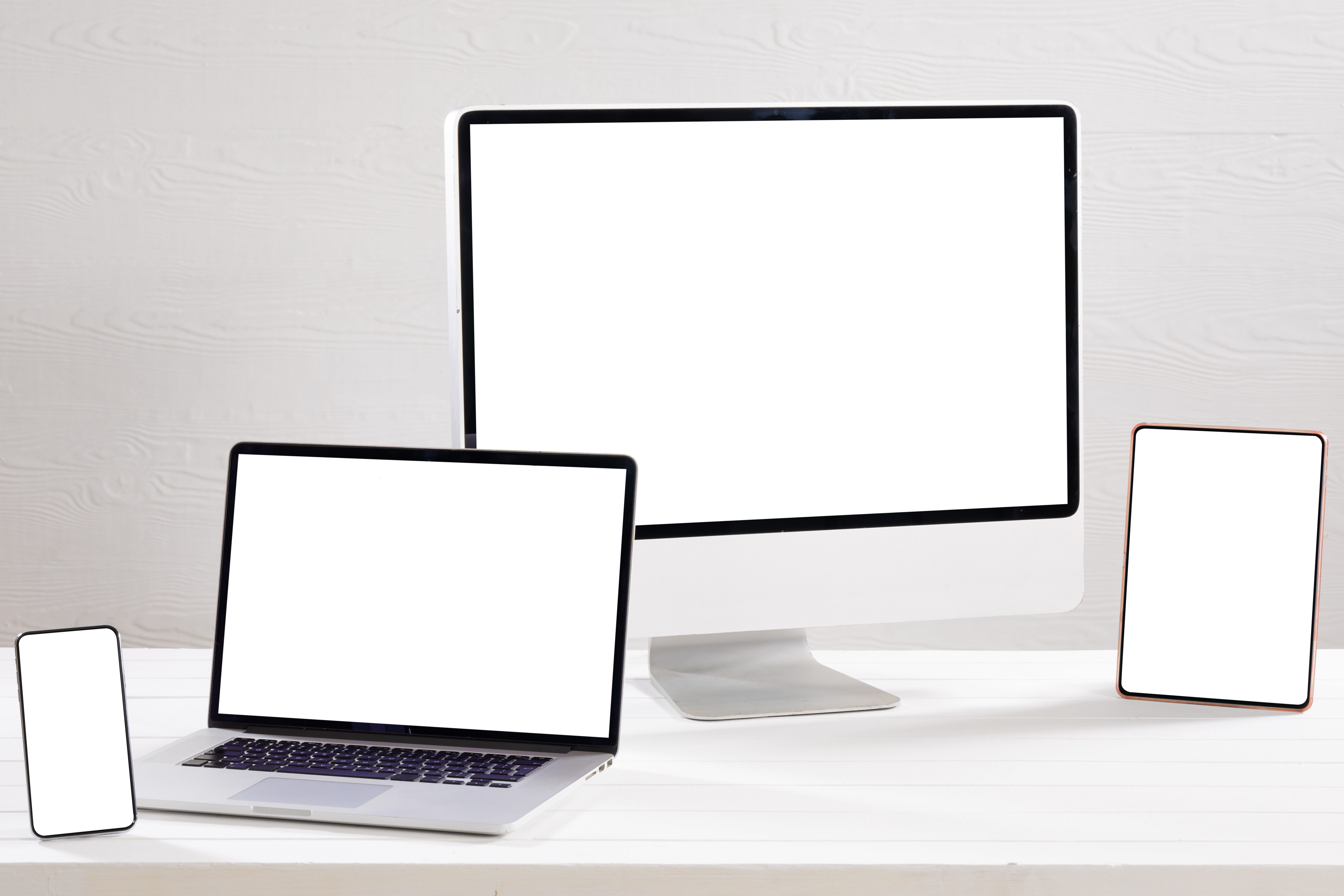 Desktop monitor, laptop, tablet and smartphone with blank screens on a white desk, responsive web design mockup